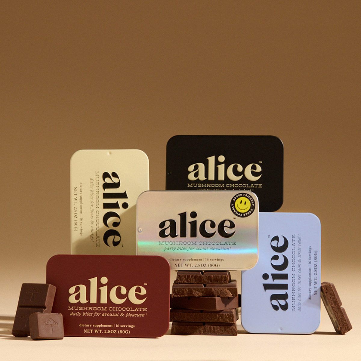 Discovery Set: five alice mushroom chocolate tins and dark chocolate squares arranged in a tan studio