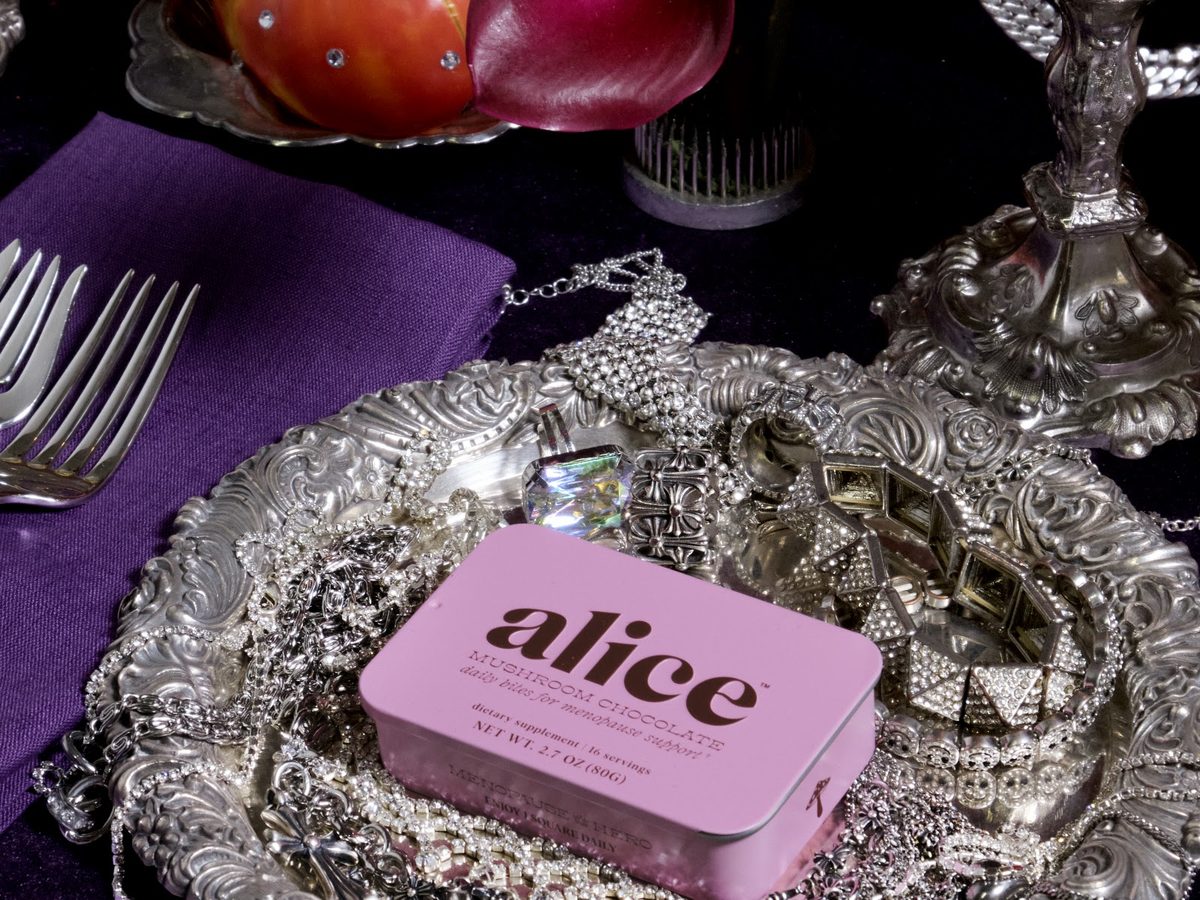 A pink Menopause Hero tin on a silver tray of jewels and silverware