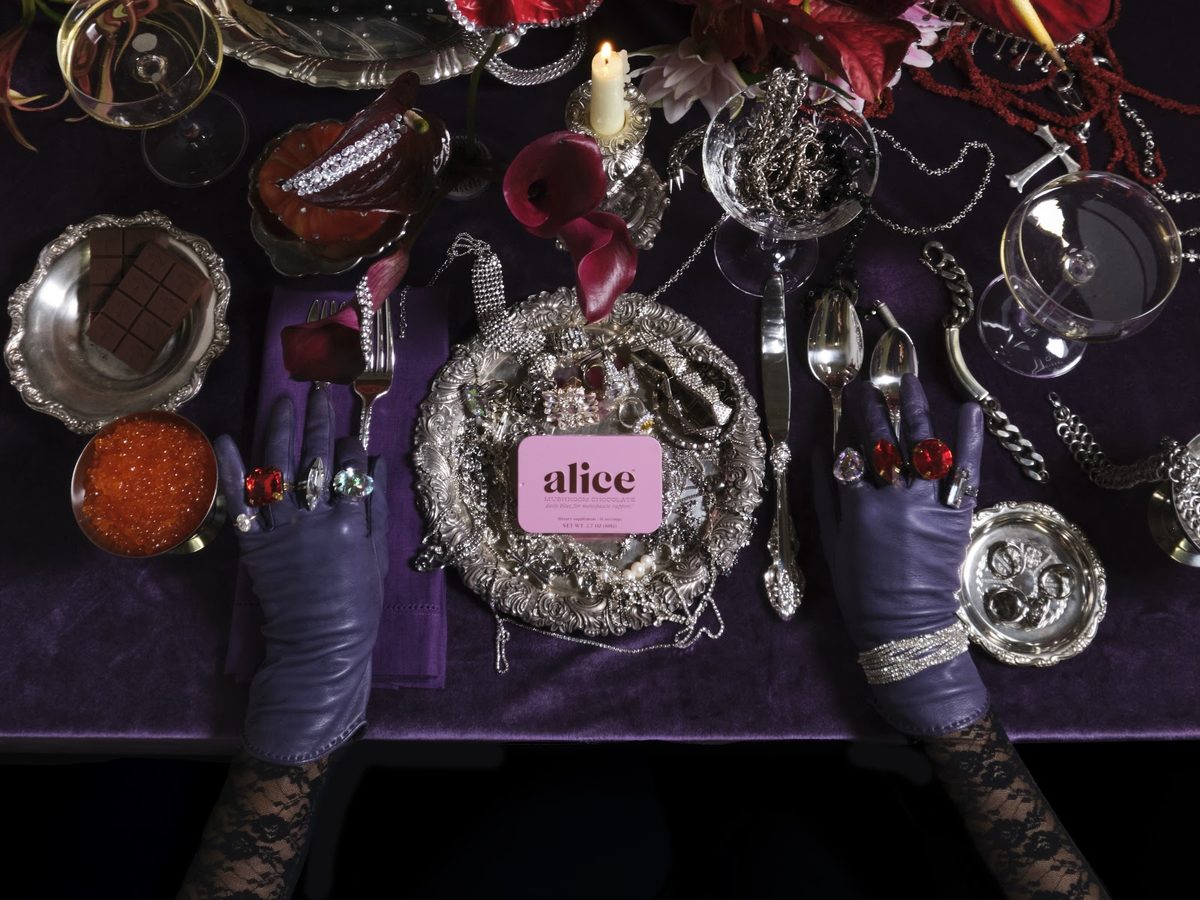 A pink Menopause Hero tin on a candlelit dinner table set with silver